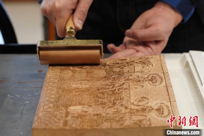 圖為徐晉林工作室工作人員正在給雕好壁畫的版面滾油墨。　九美旦增 　攝