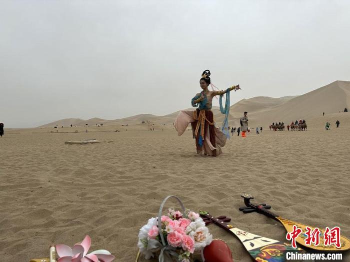 圖為2023年4月底，敦煌大漠“逐舞者”奧楠在鳴沙山月牙泉景區(qū)視頻直播敦煌舞?！●T志軍 攝