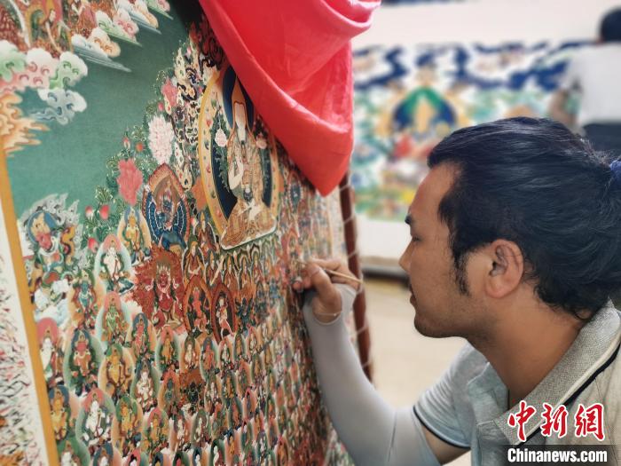 圖為更登才讓的徒弟繪畫唐卡?！?zhí)砀?攝